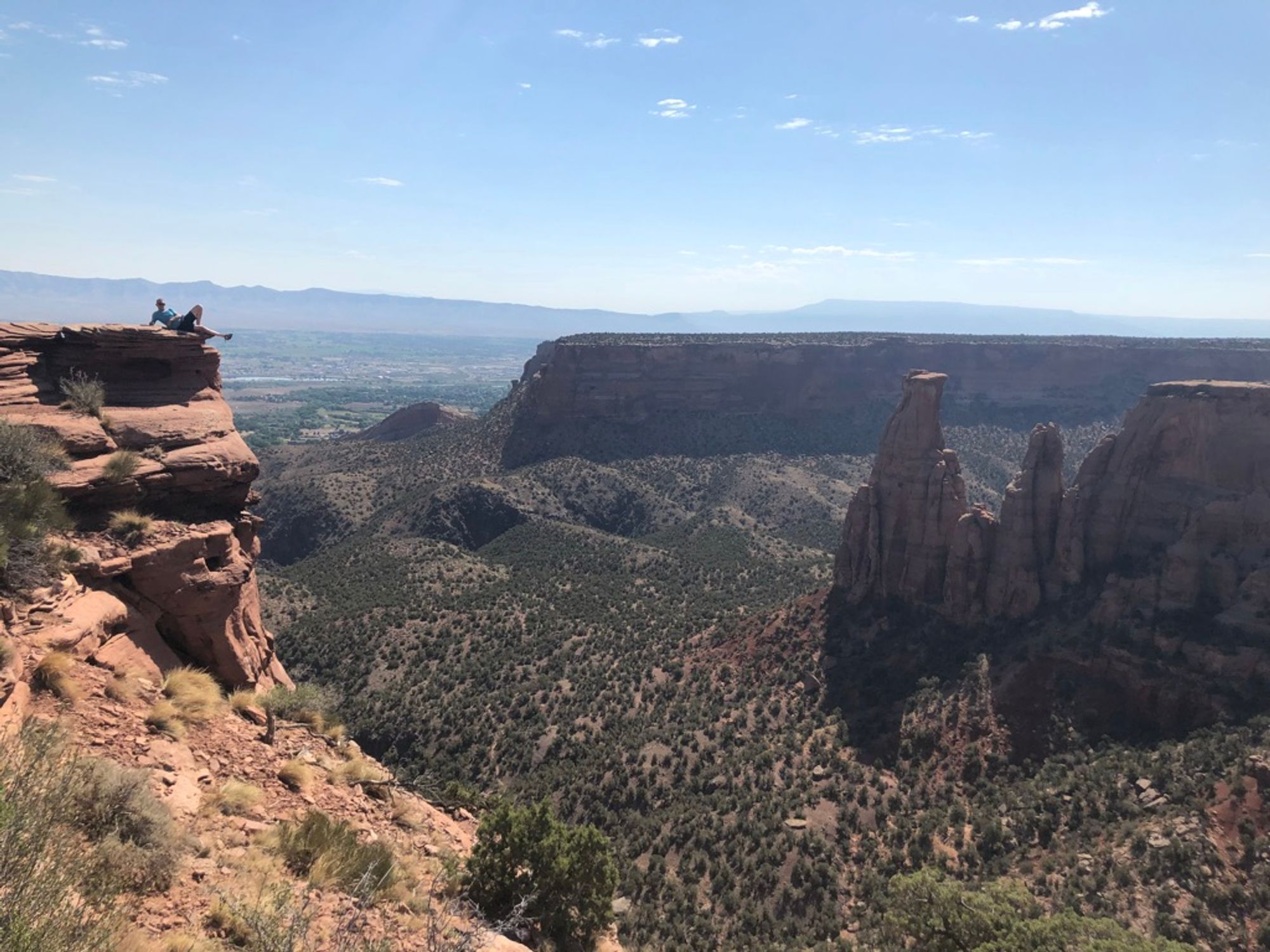 Me, in the midground, laying seductively on a cliff face with rock formations in the background.