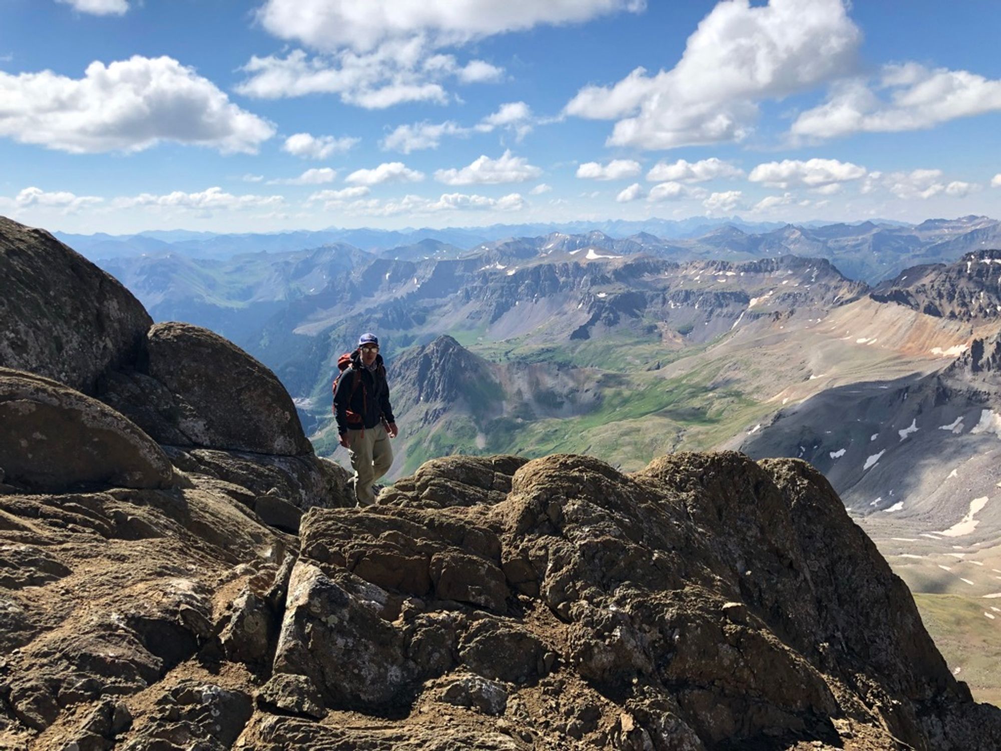 Josh hiking towards the camera and summit with the Rockies in the background