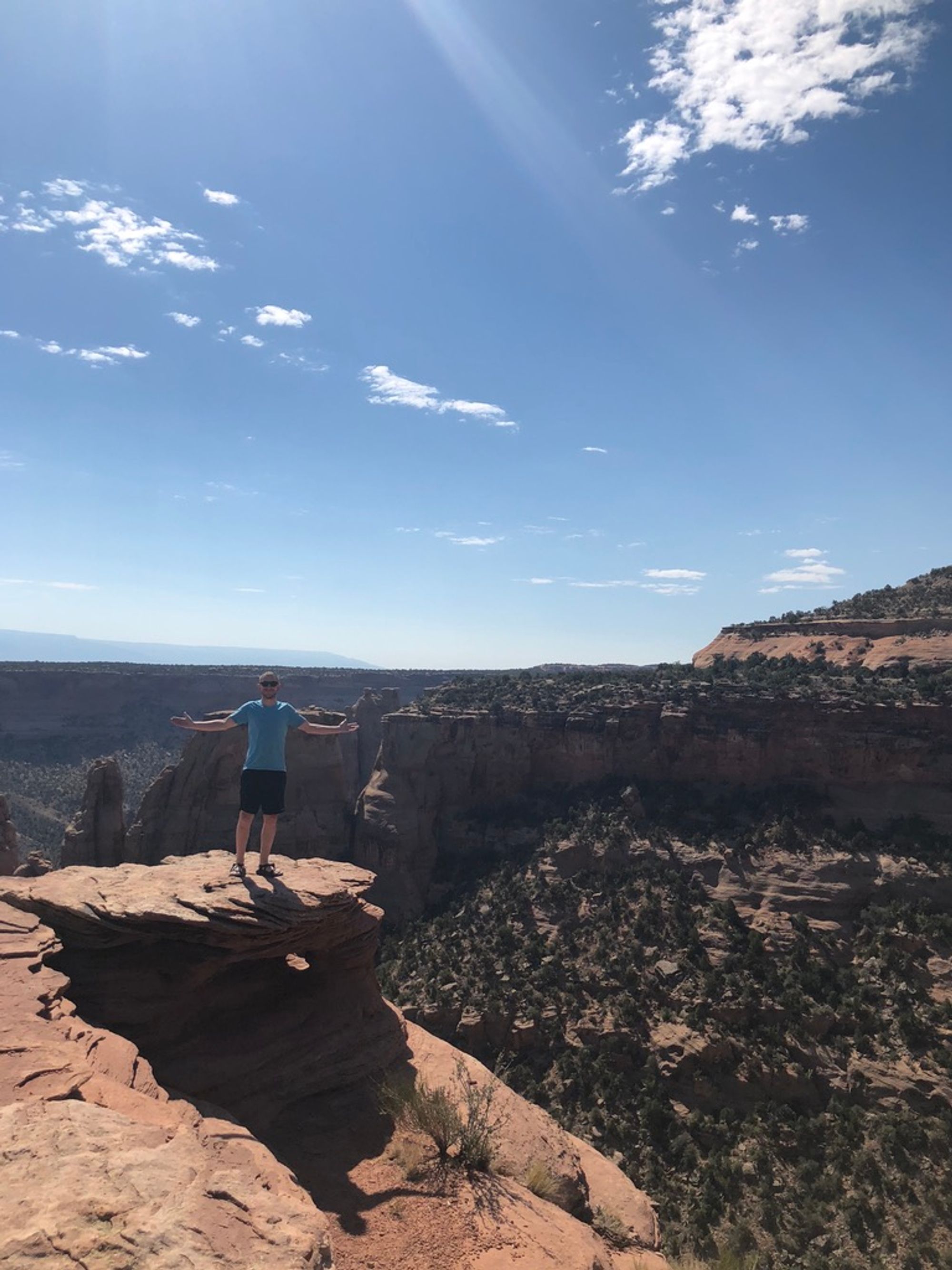 Me, in the midground, standing on a cliff face with rock formations in the background.