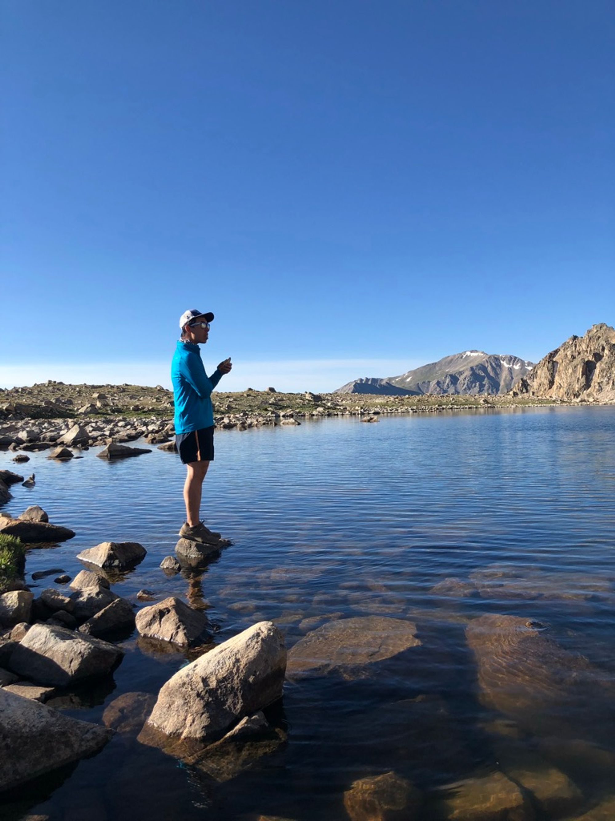 Josh eating breakfast on a rock, surrounded by the waters of Bear Lake