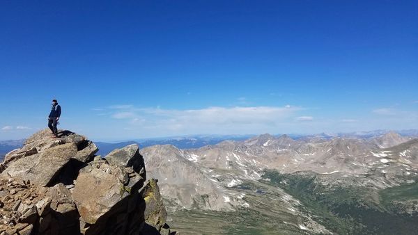 Epic shot of me in the medium distance, center-left framed, looking out from the summit